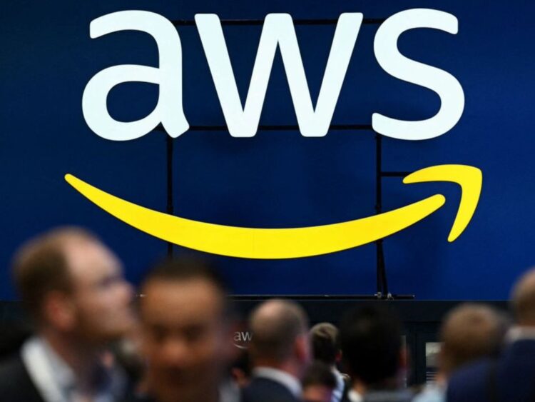 Logo de AWS en azul y blanco, con la flecha sonriente amarilla, sobre una multitud en el AWS re:Invent.