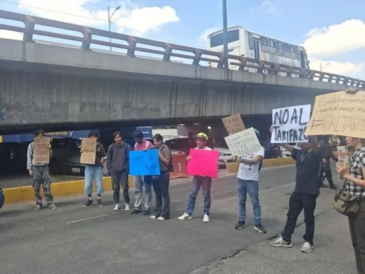 Varias personas bloquean el acceso principal frente a las oficinas de la Secretaría de Movilidad del Estado de México en Tlalnepantla, por el aumento en las tarifas al transporte. Foto Especial