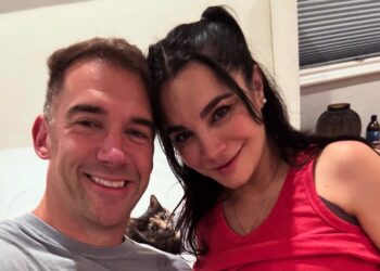 Martha Higareda y Lewis Howes sonrientes juntos en una foto ilustrativa anunciando el nacimiento de sus gemelas.