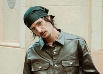 Danny Ocean durante una presentación en vivo, sosteniendo un micrófono mientras canta bajo luces cálidas.