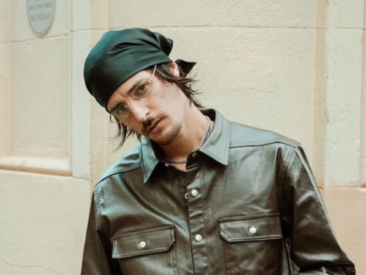 Danny Ocean durante una presentación en vivo, sosteniendo un micrófono mientras canta bajo luces cálidas.