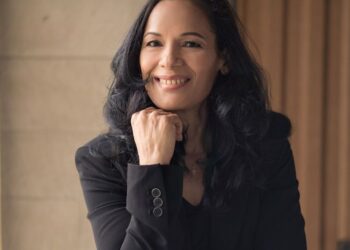 Persona sentada frente a una computadora en oficina, con gesto de cansancio y estrés, simbolizando el impacto del burnout en el trabajo y la intención de renuncia.