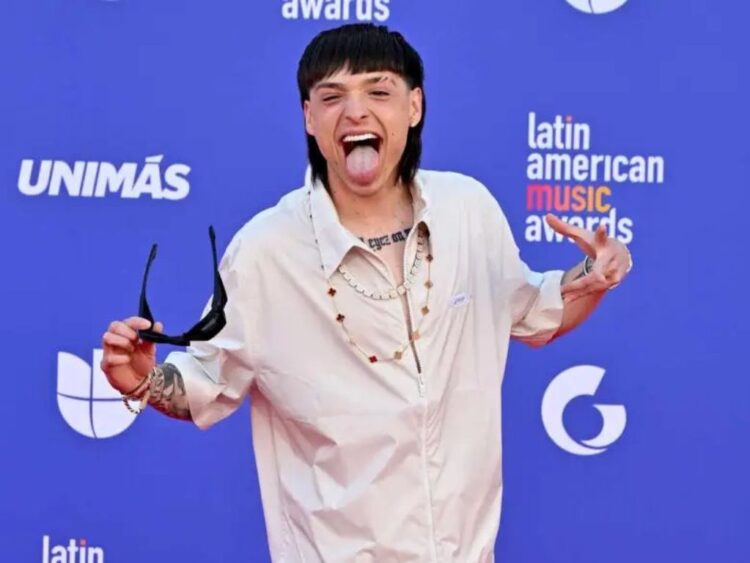 Peso Pluma en escenario durante anuncio de su gira Dinastía 2026 por Estados Unidos, con luces y público al fondo.