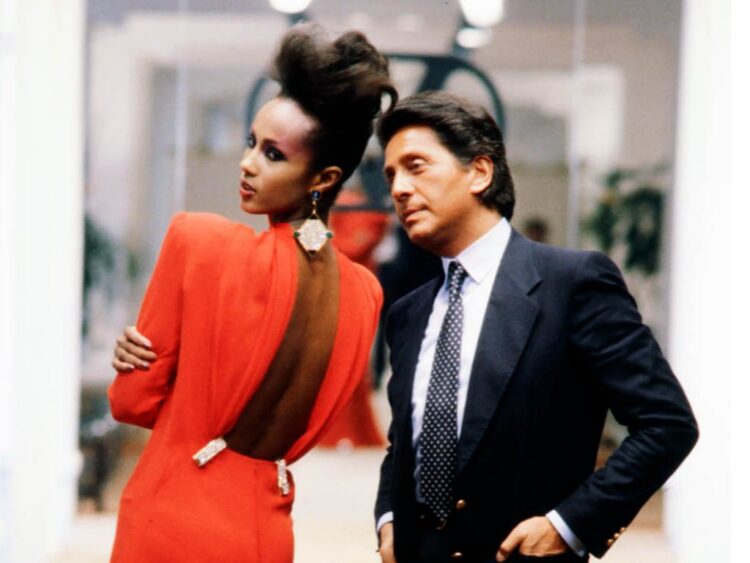 Valentino Garavani, diseñador de moda italiano, posando con una modelo que porta un vestido rojo icónico, símbolo de su legado en la alta costura.