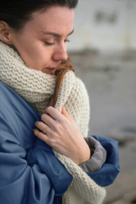 Persona aplicando crema en las manos mientras usa guantes en una mañana de clima frío para evitar resequedad y agrietamiento de la piel.