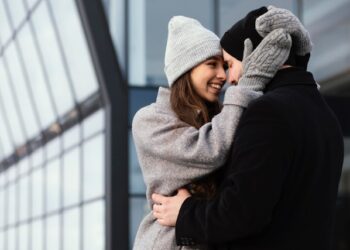 Persona aplicando crema en las manos mientras usa guantes en una mañana de clima frío para evitar resequedad y agrietamiento de la piel.