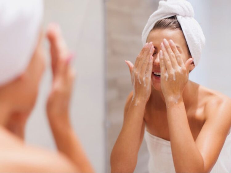 Persona lava su rostro con agua en el lavabo como parte de su rutina diaria de cuidado facial.