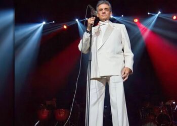 Participantes colocan listones con dedicatorias en la escultura de José José durante una ceremonia colectiva de homenaje y memoria.