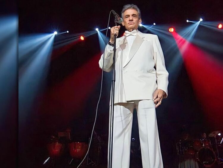 Participantes colocan listones con dedicatorias en la escultura de José José durante una ceremonia colectiva de homenaje y memoria.