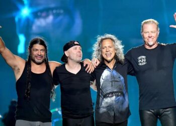 Integrantes de Metallica interpretan “Enter Sandman” en un concierto masivo, con luces intensas y miles de fans frente al escenario.