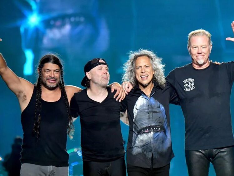 Integrantes de Metallica interpretan “Enter Sandman” en un concierto masivo, con luces intensas y miles de fans frente al escenario.