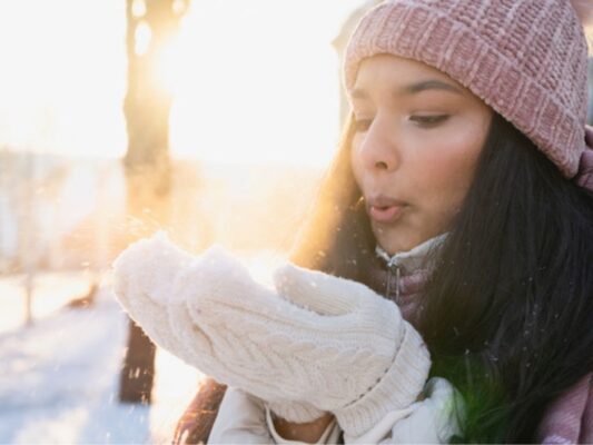 Persona aplica crema humectante en sus manos durante temporada de frío para prevenir resequedad y proteger la piel.