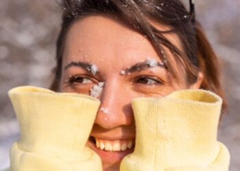 Persona aplica crema humectante en sus manos durante temporada de frío para prevenir resequedad y proteger la piel.