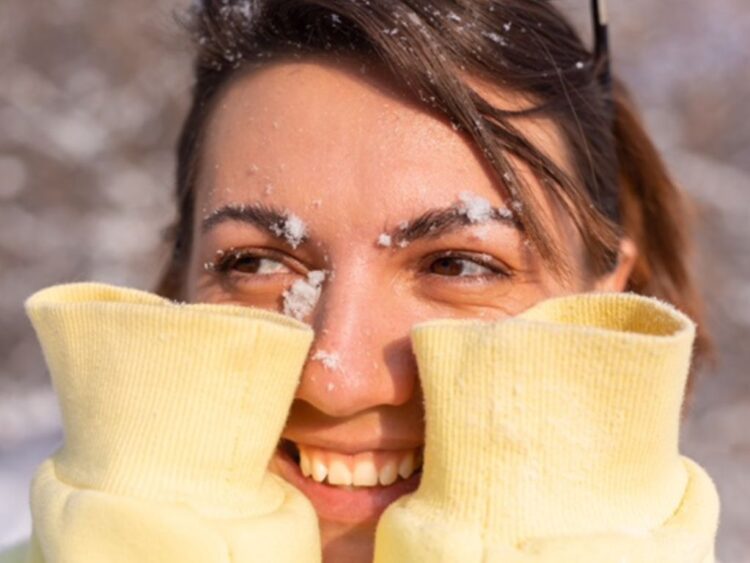 Persona aplica crema humectante en sus manos durante temporada de frío para prevenir resequedad y proteger la piel.