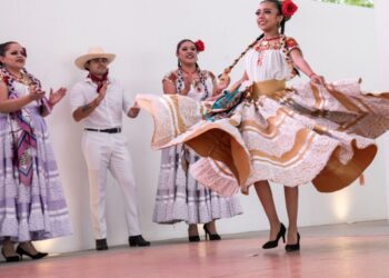 Jóvenes con atuendos tradicionales y tocados florales desfilan en el Centro Cultural Universitario de la UAM Xochimilco durante la Fiesta de la Flor Más Bella del Ejido.