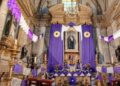 Iglesia decorada con telas moradas y sacerdote con vestimenta litúrgica durante una celebración de Semana Santa.