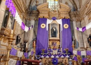 Iglesia decorada con telas moradas y sacerdote con vestimenta litúrgica durante una celebración de Semana Santa.