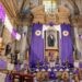 Iglesia decorada con telas moradas y sacerdote con vestimenta litúrgica durante una celebración de Semana Santa.