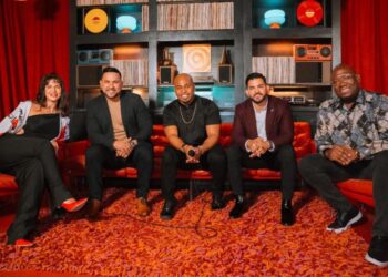 Nathy Peluso canta junto a la orquesta de Grupo Niche en un escenario durante un concierto de salsa en vivo.