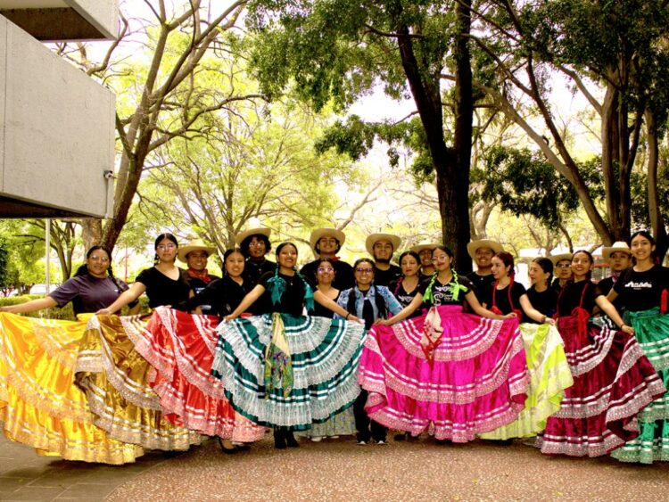 Bailarines de la UAM Azcapotzalco interpretan coreografías folclóricas inspiradas en tradiciones mexicanas en un escenario cultural.