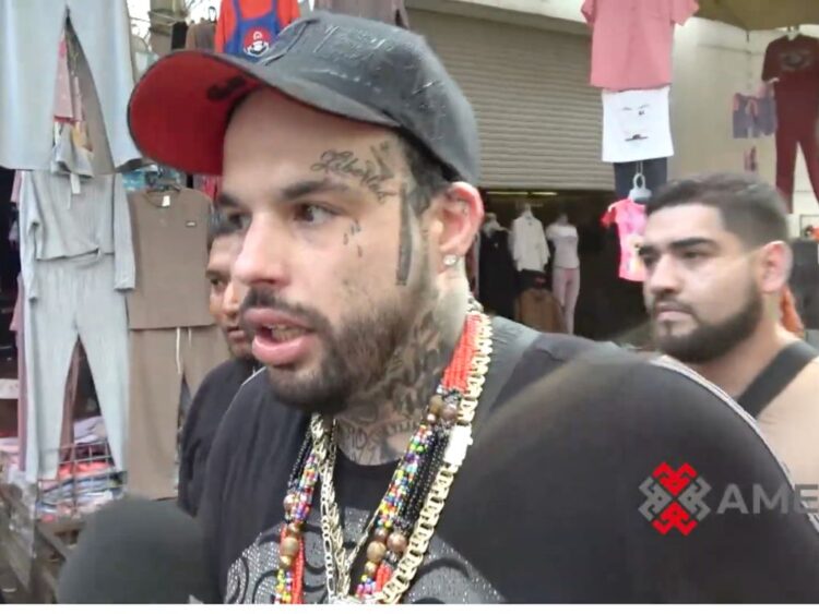 Emiliano Aguilar camina por calles de Tepito durante la grabación de su videoclip “Harley Quinn”, rodeado de un entorno urbano.