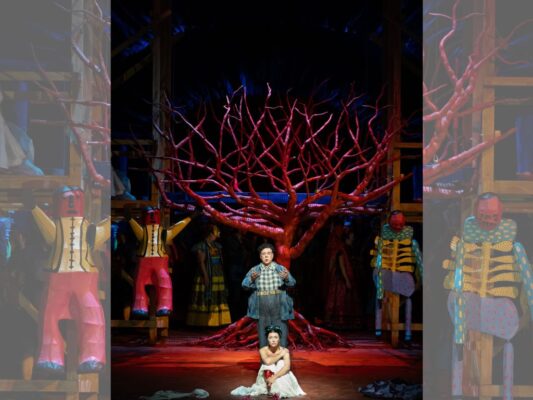Escena de la ópera El último sueño de Frida y Diego con personajes inspirados en Frida Kahlo y Diego Rivera dentro de una escenografía surrealista.