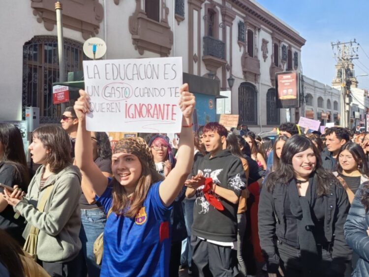 Universitaria chilena muestra un cartel contra la disminución del presupuesto para educación.