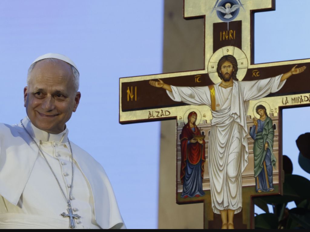 El Papa León XIV saluda frente a un crucifico