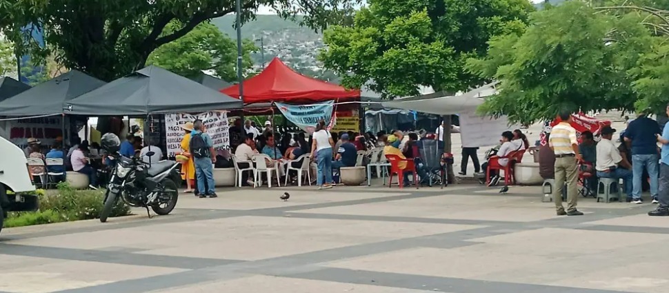 Los integrantes de la CNTE mantienen su plantón en la plaza central de esta capital instalados en casas de campaña bajo árboles, tolerando las altas temperaturas y las fuertes lluvias que caen por la tarde.