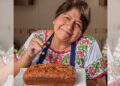 Abue Angie posa con su libro Recetario para mis nietecitos independientes durante una entrevista en la que relata cómo inició su trayectoria como creadora de contenido y promotora de la cocina casera.