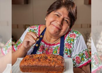 Abue Angie posa con su libro Recetario para mis nietecitos independientes durante una entrevista en la que relata cómo inició su trayectoria como creadora de contenido y promotora de la cocina casera.