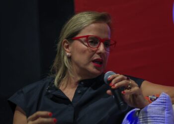 Productora Inna Payán con gafas rojas hablando por micrófono durante una conferencia magistral en el Festival Internacional de Cine Guanajuato.