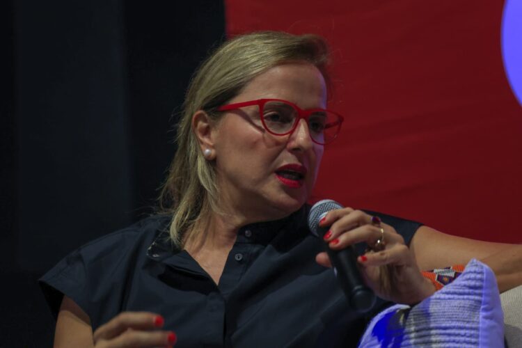 Productora Inna Payán con gafas rojas hablando por micrófono durante una conferencia magistral en el Festival Internacional de Cine Guanajuato.