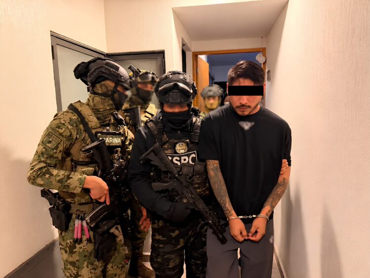 Iván Sánchez Santiago, alias El Cromo, detenido y esposado mientras es custodiado por elementos de Marina y de la Secretaría de Seguridad y Protección Ciudadana.