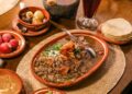 Platillo tradicional de carne en su jugo al estilo de Guadalajara, preparado con trozos de res, tocino y frijoles, acompañado de cebolla, cilantro, rábanos y limón.