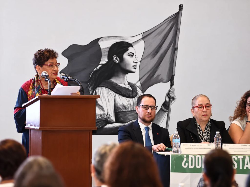 Familias buscadoras participan en una mesa de diálogo; la fiscal general de la República, Ernestina Godoy, habla desde un atril ante asistentes.