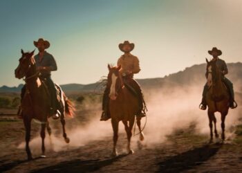 Tres hermanos de “Tierra de Amor y Coraje” montan a caballo en un paisaje de rancho