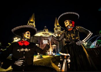 Pareja de catrines vestidos de charros posa frente a la Catedral de Guadalajara durante las celebraciones del Día de Muertos en Jalisco.