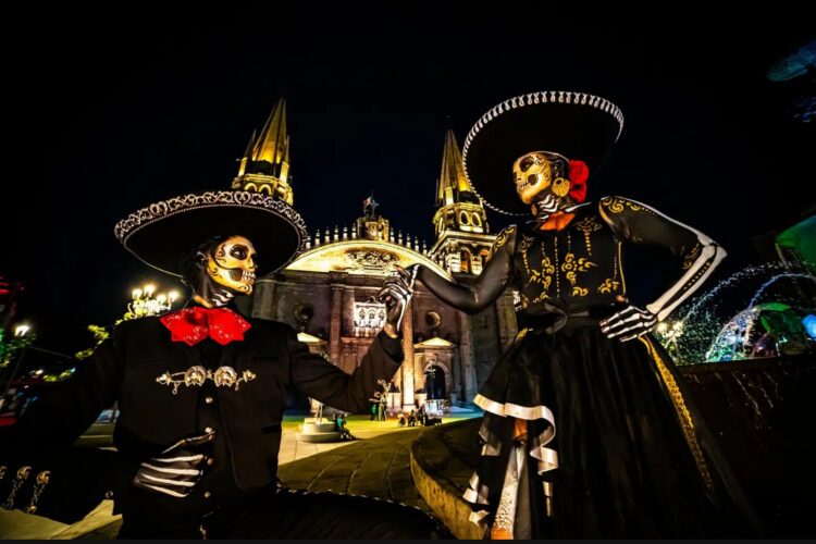 Pareja de catrines vestidos de charros posa frente a la Catedral de Guadalajara durante las celebraciones del Día de Muertos en Jalisco.