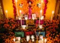 Ofrenda tradicional de Día de Muertos decorada con flores de cempasúchil, veladoras, papel picado, pan de muerto, alimentos y fotografías de seres queridos.
